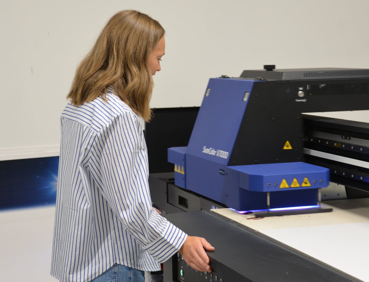 Medarbeider ved UV-skriveren med flatt bord